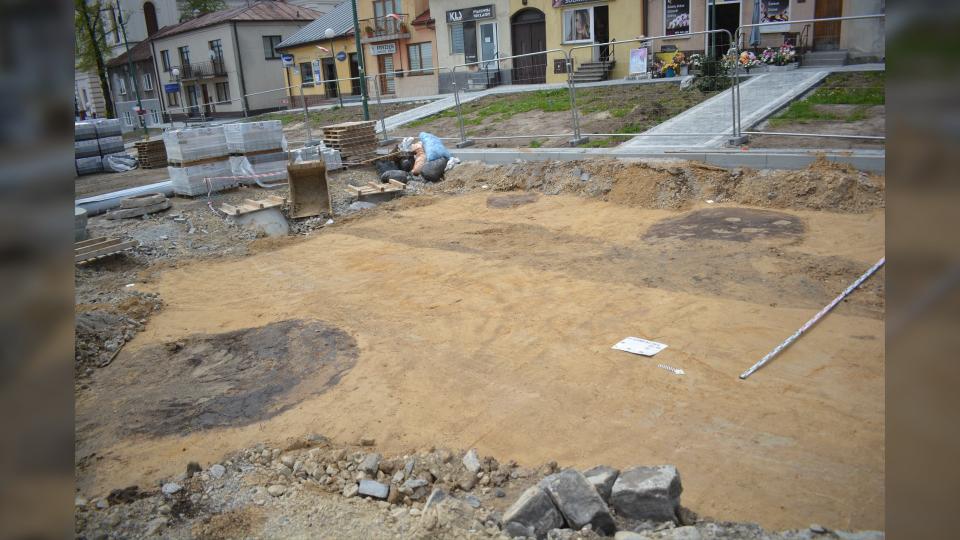 The grave and the artifacts found near the burial. Remains of pottery and lithics were found with the grave. Here we see a street dug up and cordoned off. Behind the metal fences are some shops.