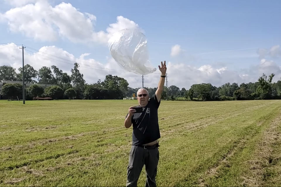 In this image taken from a video shot by Tom Medlin on June 11, 2022, Ed Harrison launches a so-called pico balloon, which costs about $12 and is about 32 inches in diameter, in a field near Collierville, Tenn. Medlin, owner of the Amateur Radio Roundtable podcast, believes a similar balloon is what the U.S. military shot down over the Yukon recently. Hobbyists typically fly the balloons for fun and to experience the challenge of building transmitters and antenna systems, although the National Oceanic and Atmospheric Administration has been collecting data from operators to learn more about wind patterns, he said. (Tom Medlin via AP)