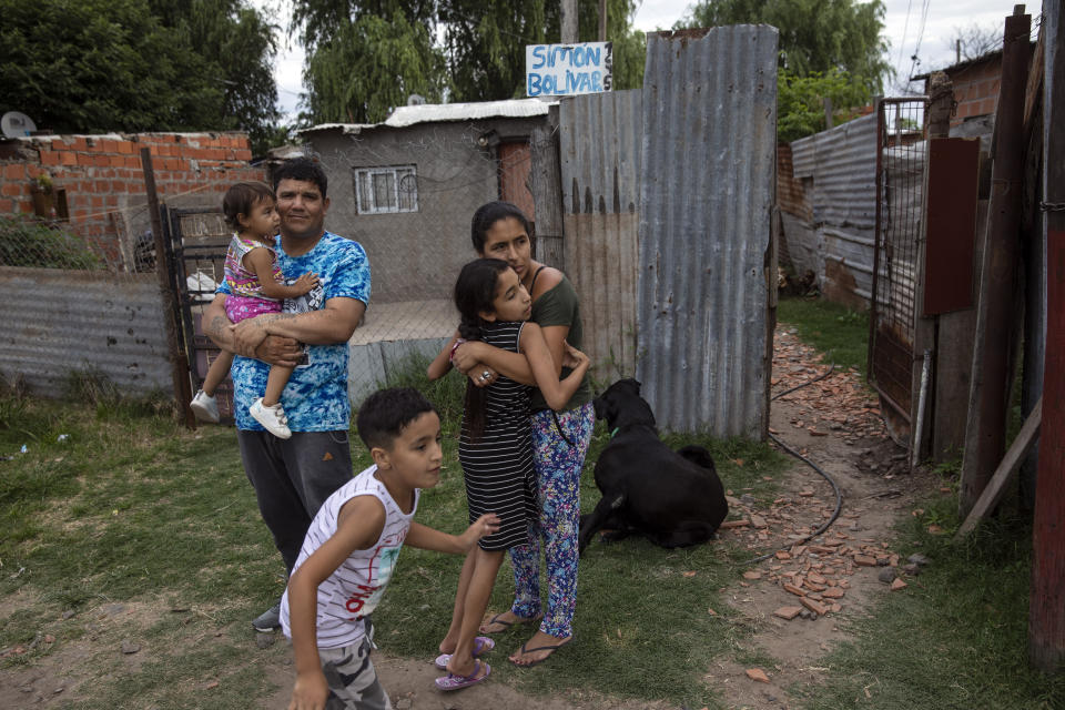 Dario Almiron stands with his family outside their home in the Villa Gobernador Galvez district on the outskirts of Rosario, Argentina, Friday, Dec. 3, 2021. Dario, released from prison three years ago after serving 20 years for robbery and homicide, ministers to inmates at several prisons. (AP Photo/Rodrigo Abd)
