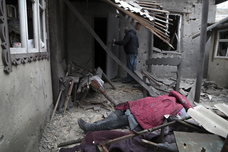 A body of woman, killed during shelling, lies under debris of a damaged house in Donetsk, in the territory controlled by pro-Russian militants, eastern Ukraine, Friday, Feb. 25, 2022. The Russian military is pressing its invasion of Ukraine to the outskirts of the capital. The advancement came after Russia unleashed airstrikes on cities and military bases and sent in troops and tanks from three sides in an attack that could rewrite the global post-Cold War security order. (AP Photo/Alexei Alexandrov)