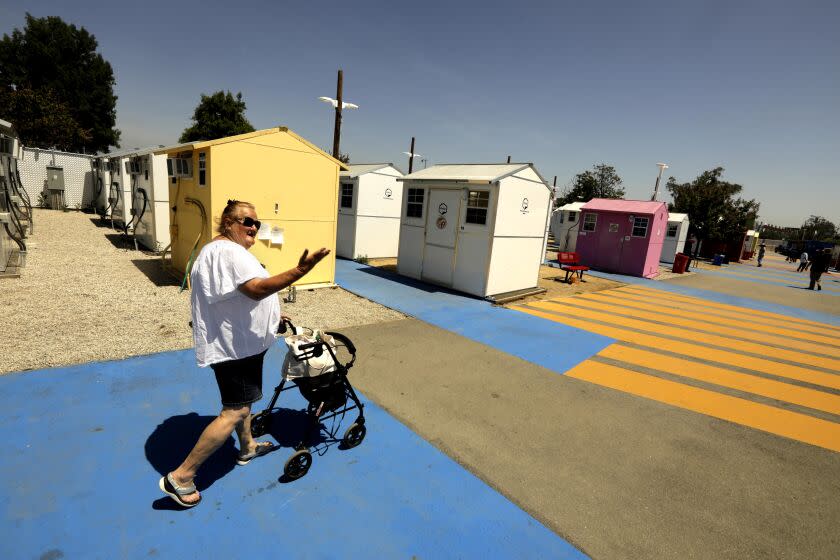 NORTH HOLLYWOOD, CA - APRIL 27, 2023 - Beth Thompson, 58, who is a chronically homeless, makes her way to her home at the Alexandria Park Tiny Home Village in North Hollywood on April 27, 2023. She's been teamed up by a nonprofit called Miracle Messages with a phone buddy in Maryland. The two women speak regularly by phone and text. After sticking with the relationship for several months, Beth started receiving a stipend of $750 per month. It's part of an experiment to show that companionship, augmented by some spending money, can ease people's path out of homelessness. (Genaro Molina / Los Angeles Times)