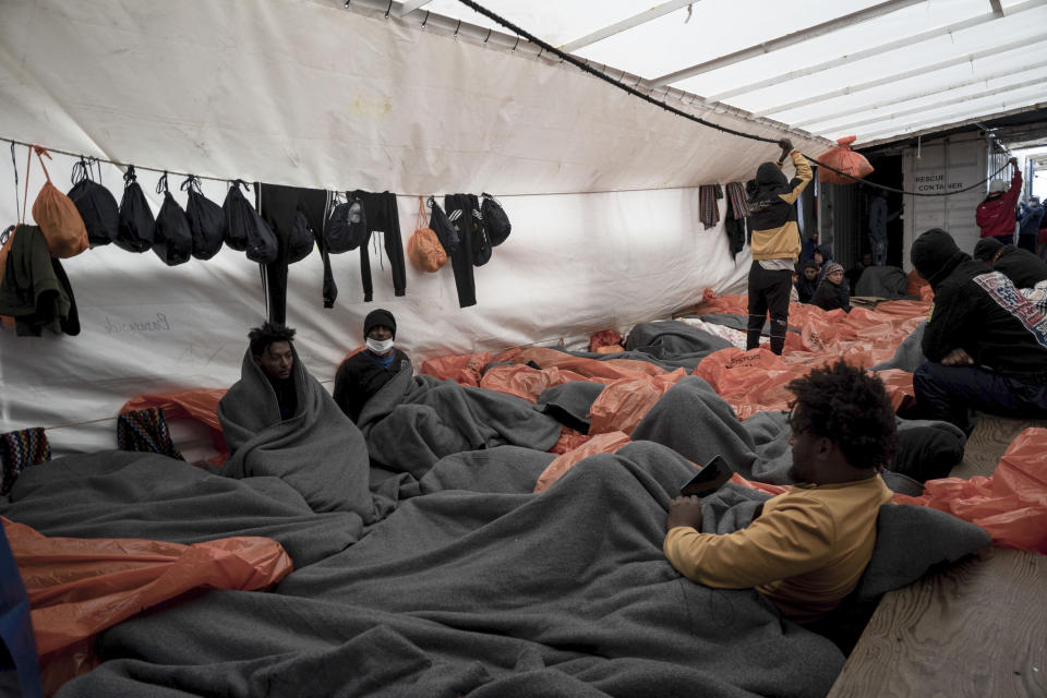 Migrants wrapped in blankets and waterproof bags lie on the deck of the Ocean Viking rescue ship, in the Strait of Sicily, in the Mediterranean Sea, Saturday, Nov. 5, 2022. (AP Photo/Vincenzo Circosta)