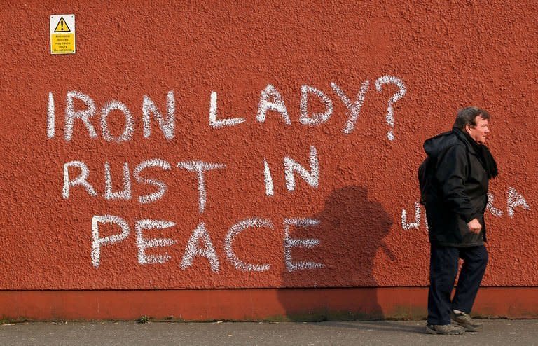 A pedestrian walks past graffiti that reads "Iron Lady? Rust in Peace" refering to former British prime minister Margaret Thatcher in west Belfast, Northern Ireland, on April 9, 2013