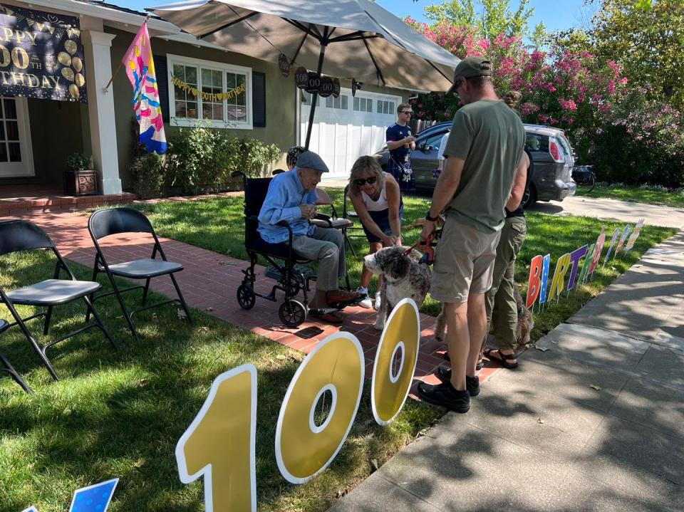 Robert Moore pets a dog at his 100th birthday party