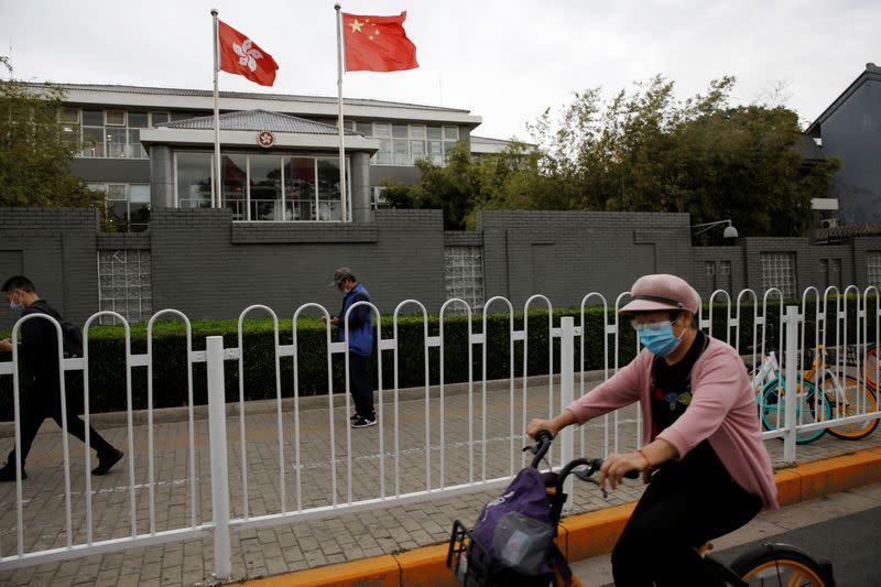 People travel past Chinese and Hong Kong flags in Beijing