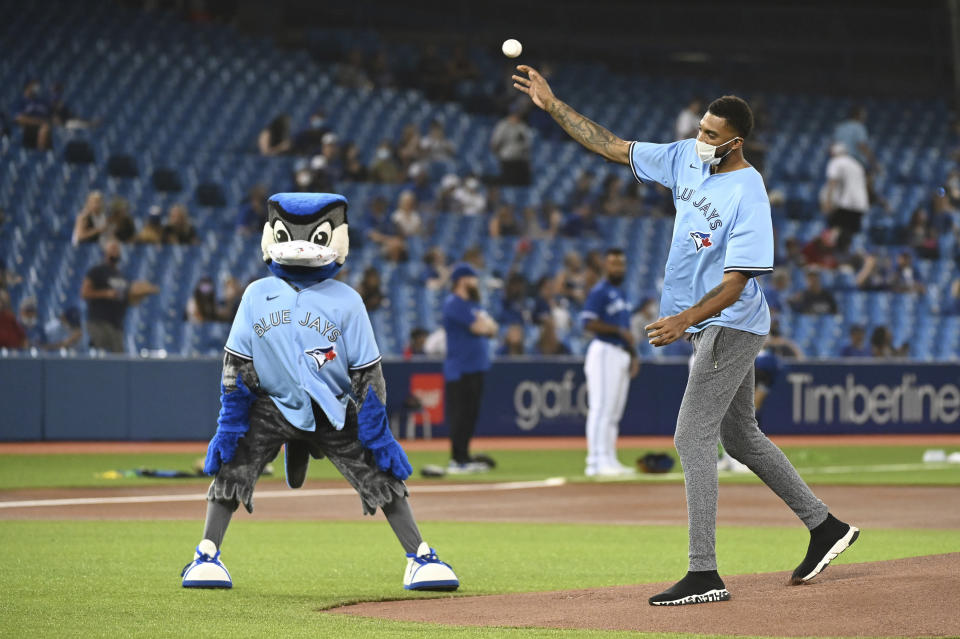 Toronto Raptors' Khem Birch, right, throws out the ceremonial first pitch before the first baseball game of a doubleheader between the Boston Red Sox and the Toronto Blue Jays in Toronto, Saturday Aug. 7, 2021. (Jon Blacker/The Canadian Press via AP)