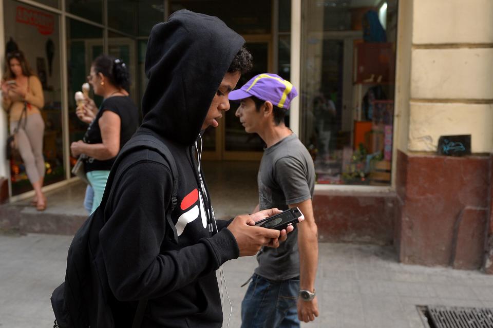 A youngster uses his mobile phone to connect to internet in Havana, Cuba. Photo: Photo credit should read YAMIL LAGE/AFP/Getty Images)