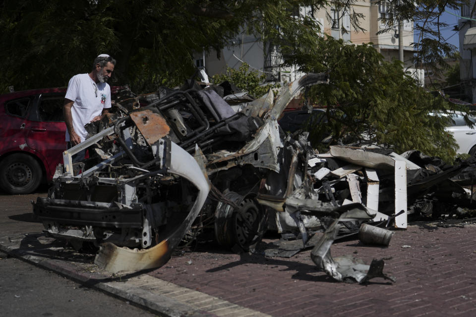 A man looks at the car destroyed by a rocket fired from the Gaza Strip in Ashkelon, Israel, Saturday, Oct. 21, 2023. (AP Photo/Tsafrir Abayov)