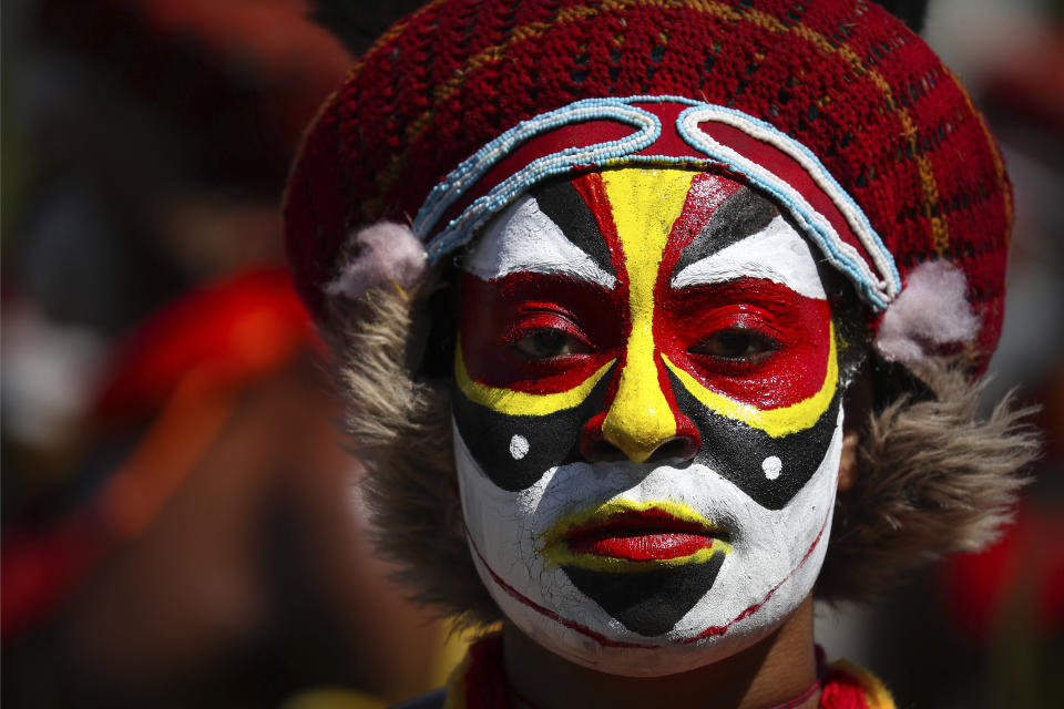 A performer in traditional clothing and makeup waits for the start of a welcome ceremony for Chinese President Xi Jinping in Port Moresby, Papua New Guinea, Friday, Nov. 16, 2018. The largely undeveloped South Pacific nation of more than 8 million mostly subsistence farmers hopes the rare world attention generated by its hosting of the Asia Pacific Economic Economic Cooperation meetings will highlight its potential and draw more investors and aid. (AP Photo/Mark Schiefelbein)