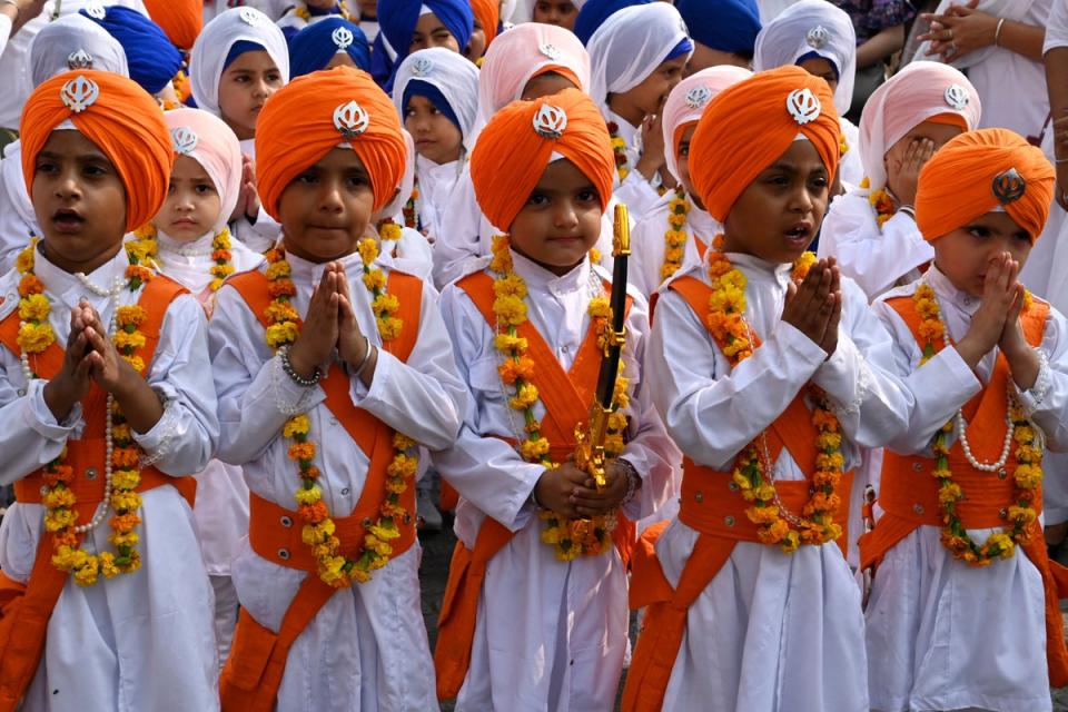Schoolchildren dressed as Sikh holy men known as Panj Pyare, gesture during a religious procession on the eve of the birth anniversary of Guru Nanak Dev, at the Golden Temple in Amritsar (AFP via Getty Images)