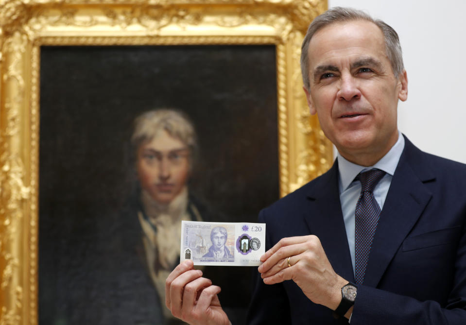 Mark Carney, Governor of The Bank of England displays the new 20 pound note in front of a self portrait of JMW Turner during a photo opportunity at the Tate Britain in London, Thursday, Feb. 20, 2020. The new 20 pound note featuring the artist JMW Turner enters circulation on Feb. 20. (AP Photo/Frank Augstein)