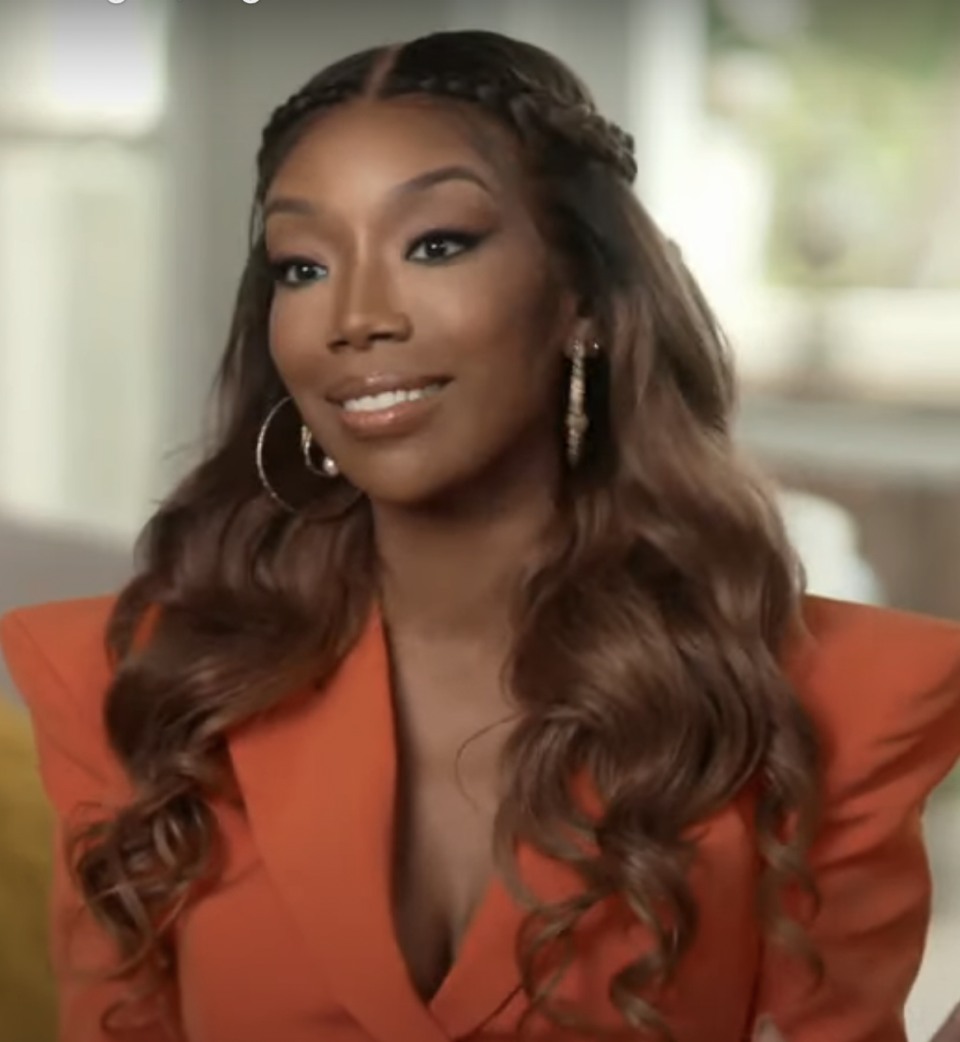 Brandy in an orange suit being interviewed during the "Cinderella" reunion