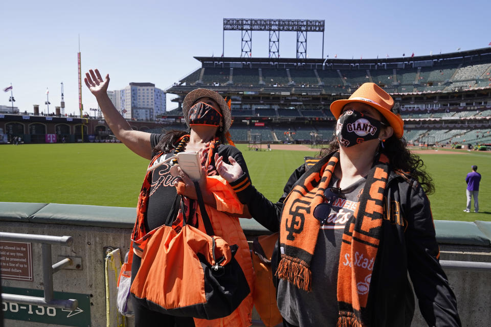 Jeanne Sweet, left, and her sister Erin Sweet, of Sebastopol, Calif., react while seeing their seats and friends in the outfield bleachers before the start of an opening day baseball game between the San Francisco Giants and the Colorado Rockies, Friday, April 9, 2021, in San Francisco. (AP Photo/Eric Risberg)