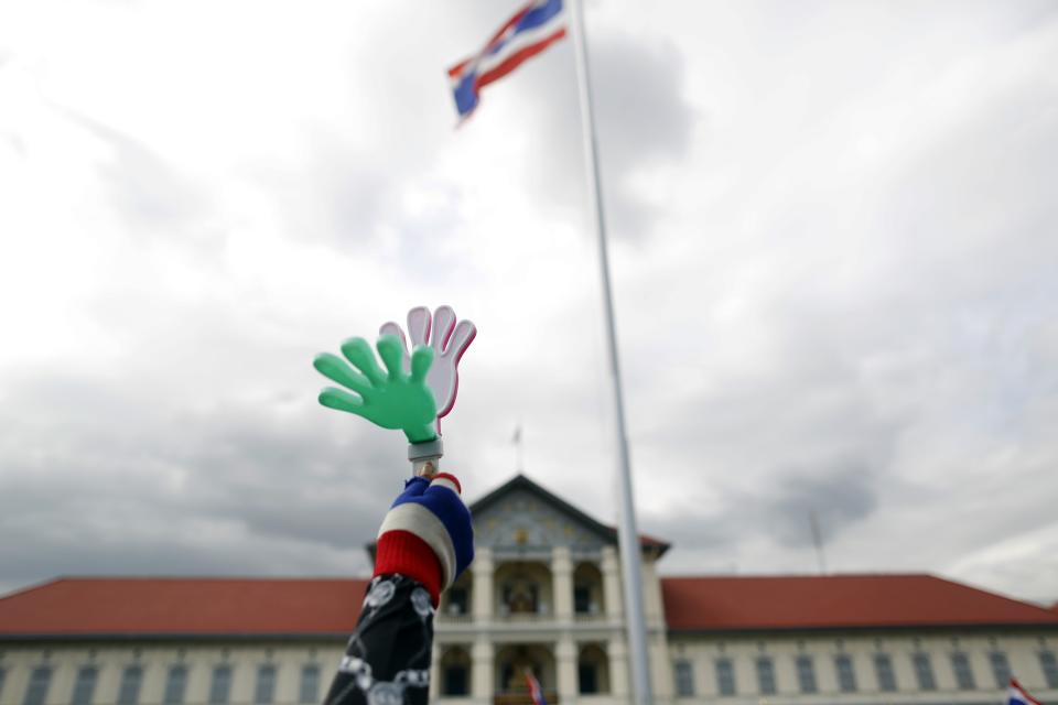 An anti-government protester waves a clapper after breaking into the compound of the Royal Thai Army headquarters in Bangkok