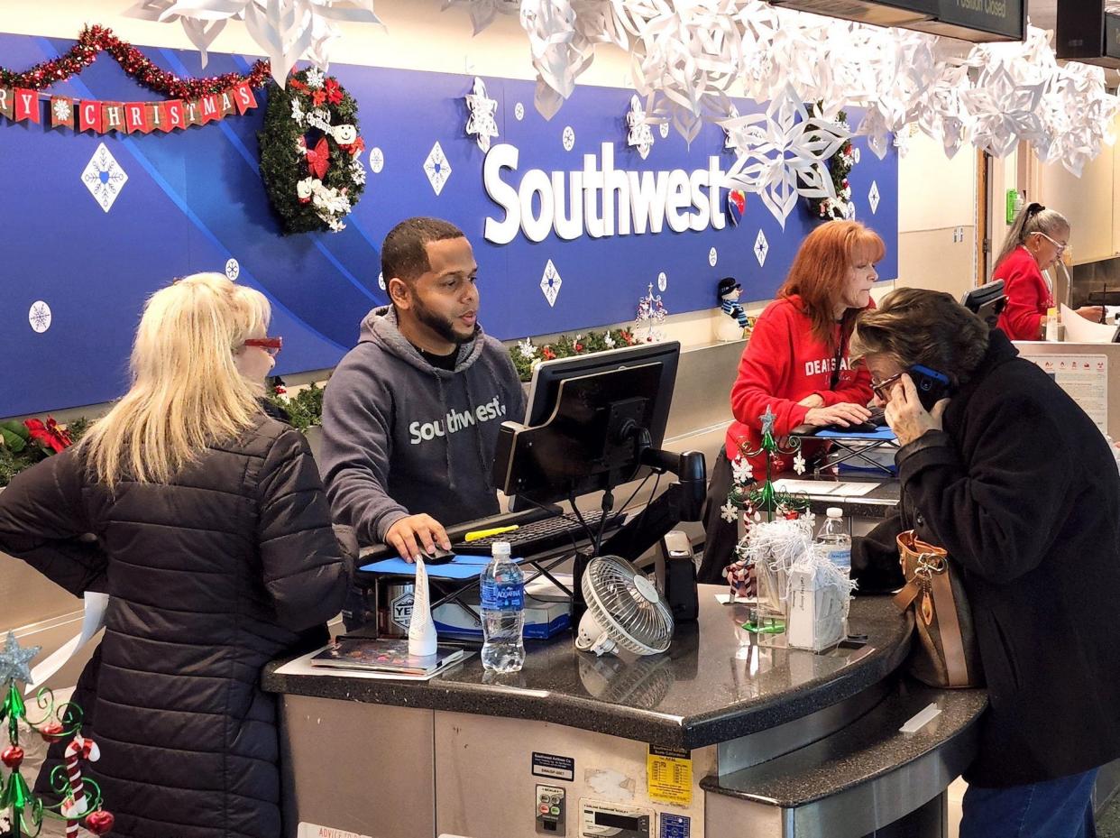 A man stands at a Southwest counter helping flyers.