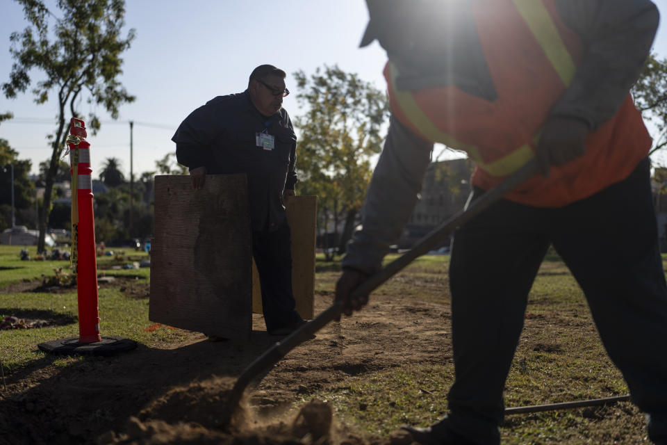 Carlos Herrera, left, a maintenance worker at the Los Angeles County Cemetery, prepares for a communal burial ceremony for the county residents who died unclaimed in the Boyle Heights neighborhood of Los Angeles, Tuesday, Dec. 12, 2023. This year's service on Dec. 14 laid to rest 1,937 people who died unclaimed in 2020. They were immigrants, children, people experiencing homelessness or poverty, and, for the first time, victims of the coronavirus. (AP Photo/Jae C. Hong)