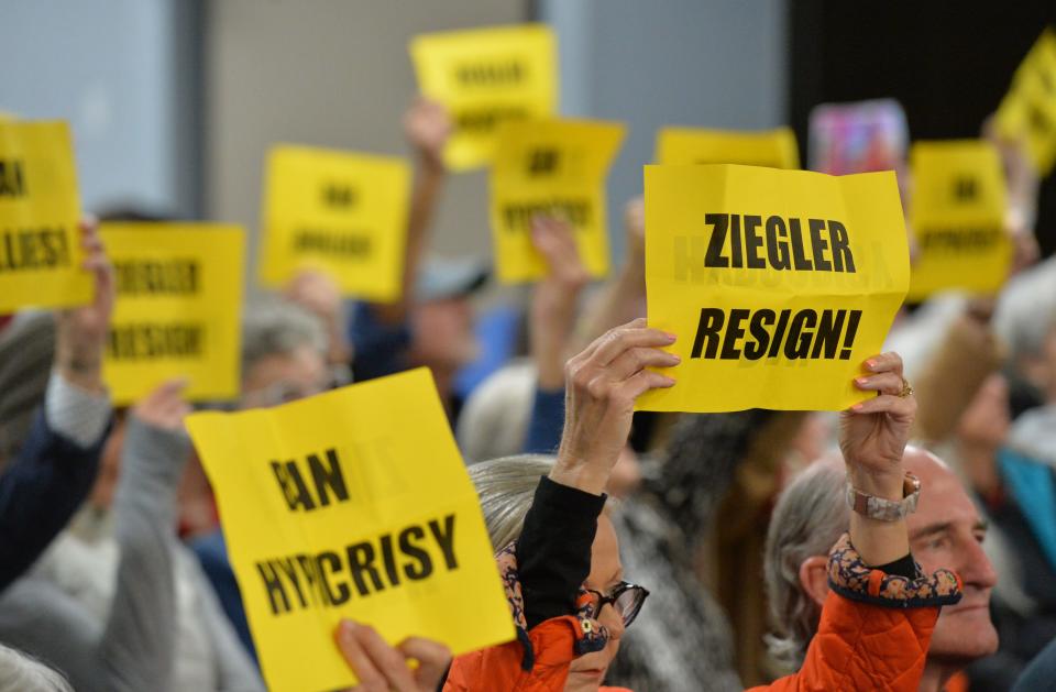 Audience members hold up signs aimed at School Board member Bridget Ziegler, during the public comment portion of the Sarasota County School Board meeting Tuesday night, Feb. 6, 2024.