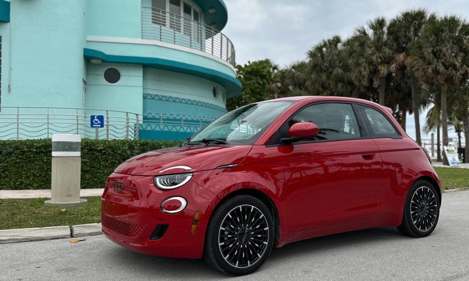 small red car in front of blue building and palm trees