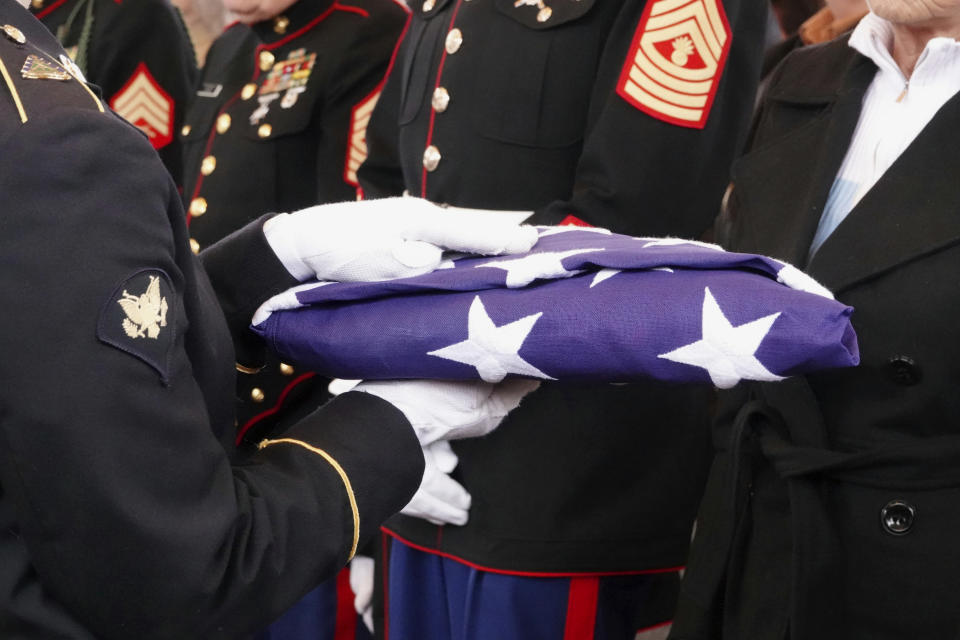 In this Jan. 17, 2019 photo, a flag is passed through a crowd of mourners as hundreds of people grieved three Memphis veterans, Wesley Russell, 76, Arnold Klechka, 71, Charles Fox, 60, who died this past fall and whose remains were unclaimed in Memphis, Tenn. Funeral homes, medical examiners, state and federal veterans’ affairs departments, and local veterans’ groups have combined forces to honor members of the military whose bodies were not claimed by any relatives. (AP Photo/Karen Pulfer Focht)