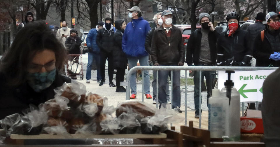 People wearing masks gather to form a "bread" line at Bread Alone outdoor market, while standing apart from each other to maintain social distancing requirements during the COVID-19 outbreak, Saturday April 4, 2020, in the Brooklyn borough of New York. (AP Photo/Bebeto Matthews)