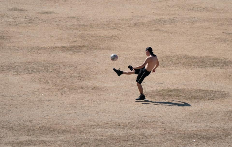 People play football on parched grass on Parker’s Piece in Cambridge, as a drought has been declared for parts of England (Joe Giddens/PA). (PA Wire)