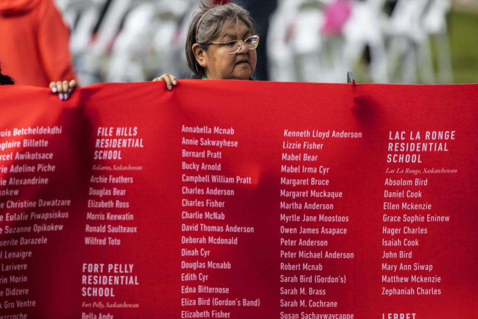 A person holds a banner with the names of children who died in Residential Schools at Pope Francis’s appearance in Maskwacis, Alta., on July 25, 2022. THE CANADIAN PRESS/Jason Franson