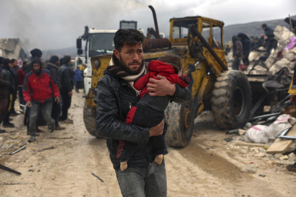 FILE - A man carries the body of an earthquake victim in the Besnia village near the Turkish border, Idlib province, Syria, Feb. 6, 2023. A year after the devastating 7.8 magnitude earthquake struck southern Turkey and northwestern Syria, a massive rebuilding effort is still trudging along. The quake caused widespread destruction and the loss of over 59,000 lives. (AP Photo/Ghaith Alsayed, File)