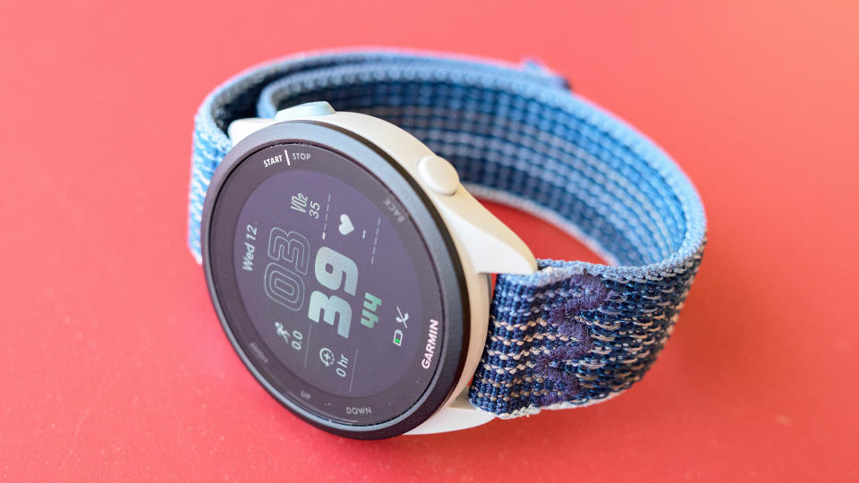 The Garmin Forerunner 165 GPS watch on a user's wrist with a blue woven band attached