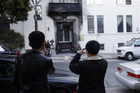 People take photographs of the damaged front door of the Chinese consulate after an unidentified person set fire to the main gate in San Francisco, California January 2, 2014. REUTERS/Stephen Lam