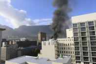 A plume of smoke arises above the Houses of Parliament, behind the St. George's Cathedral, in Cape Town, South Africa, Sunday, Jan. 2, 2022. Firefighters have been deployed and the cause is unknown. (AP Photo/Tsvangirayi Mukwazhi)