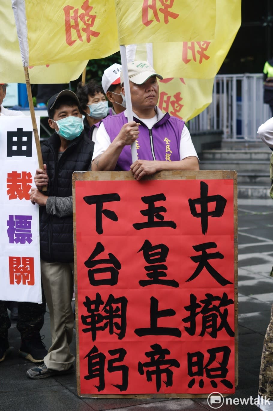 一位抗議民眾在現場拿著「中天撤照 玉皇大帝 下台鞠躬」標語。   圖：張良一/攝