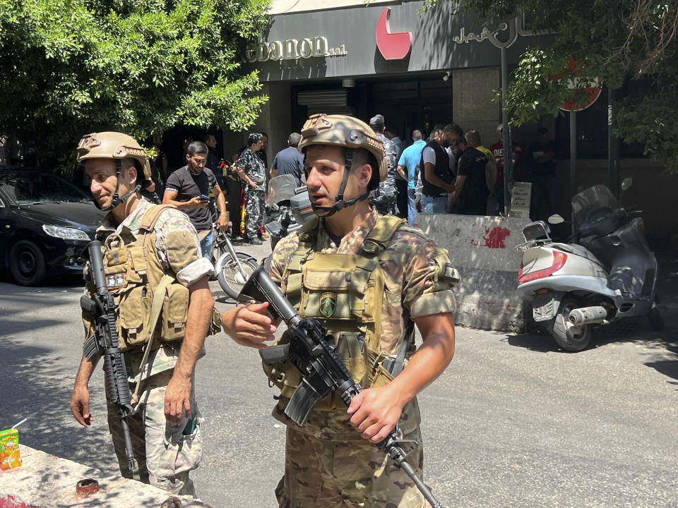 Lebanese security forces secure the area outside a bank in Beirut,, Lebanon, Thursday, Aug. 11, 2022. A Lebanese security official says a man armed with a shotgun has broken into a Beirut bank, holding employees hostage and threatening to set himself ablaze with gasoline unless he receives his trapped saving. (AP Photo/Hussein Malla)