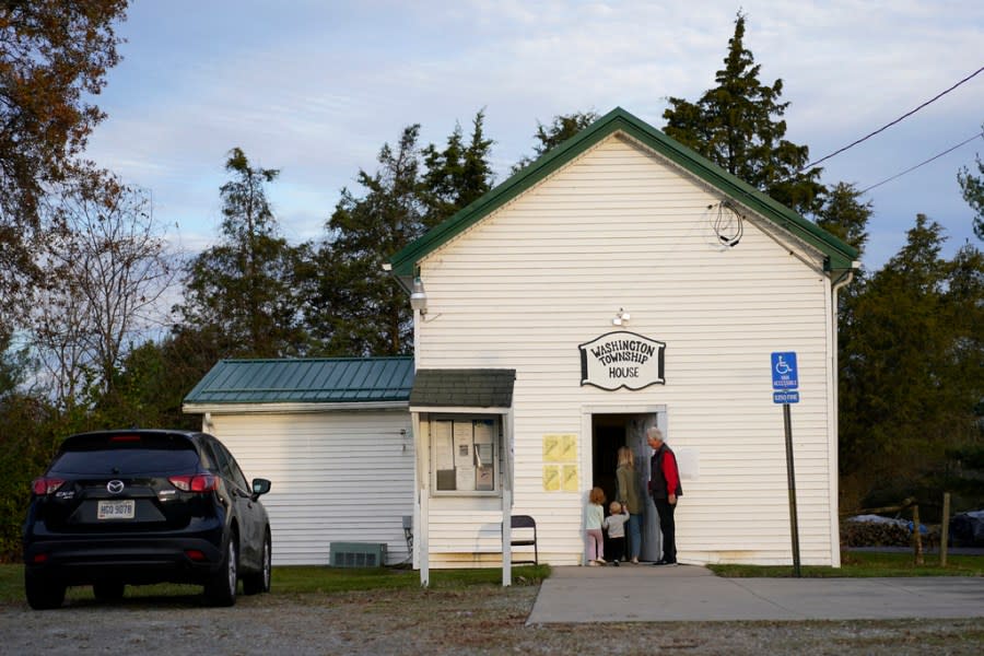 Precinct election official Andrew Kleiman, right, opens the door for Lauren Miracle, and her children Dawson, 1, and Oaklynn, 3, at a polling location in the Washington Township House in Oregonia, Ohio, Tuesday, Nov. 7, 2023. Polls are open in a few states for off-year elections that could give hints of voter sentiment ahead of next year’s critical presidential contest. (AP Photo/Carolyn Kaster)