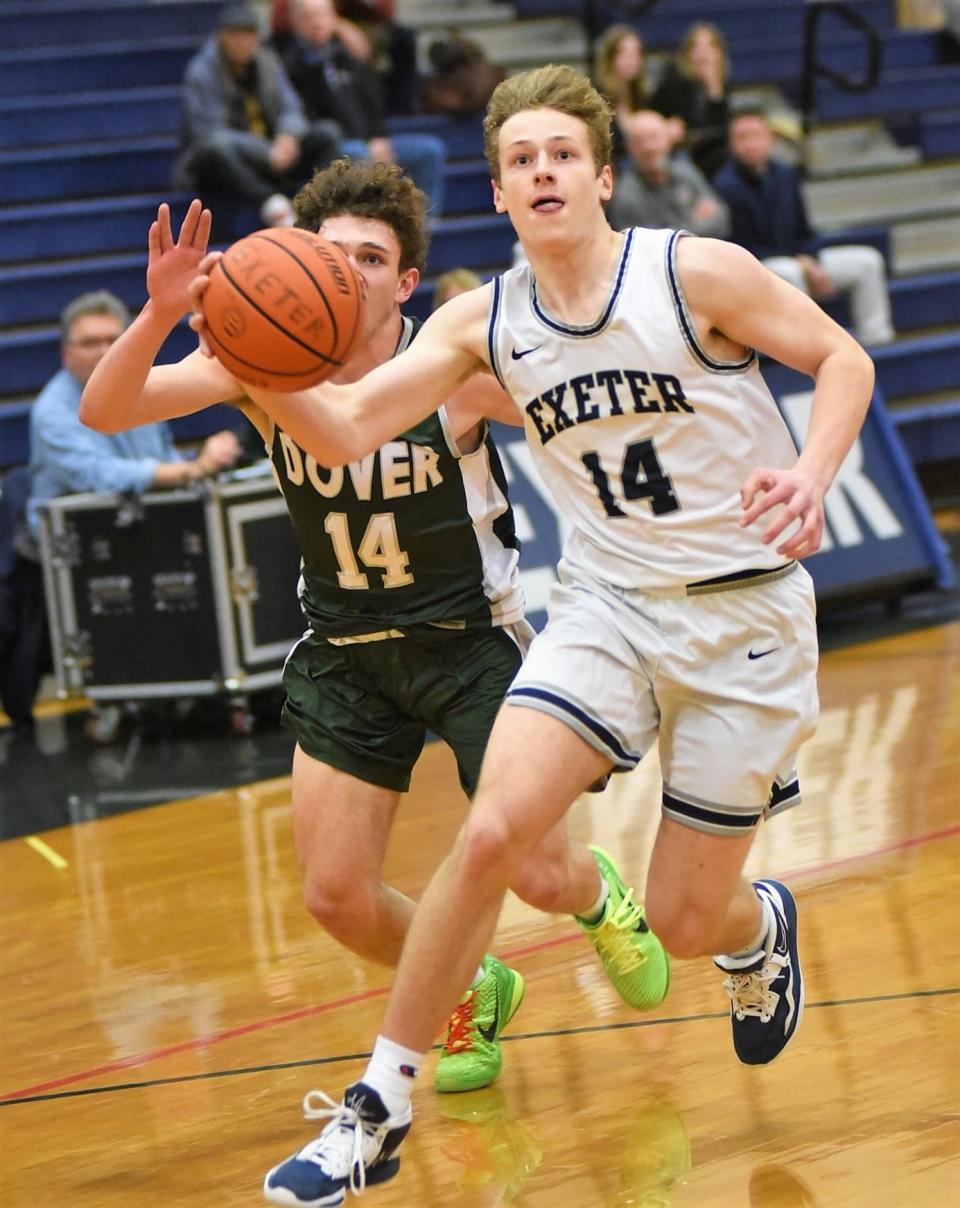Exeter's Matt Cromer heads in for a breakaway layup ahead of Dover's Dylan Labre during Tuesday's Division I boys basketball game in Exeter.