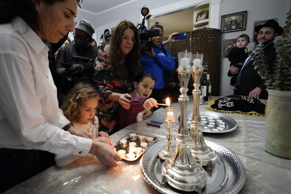 Members of the Chabad of Evanston, Ill., Yehudis Hecht, center, and her daughter Chana, and Maayan Hill, left, and her daughter Emilia, where Judith Raanan attended, light candles to mark the beginning of Shabbat on Friday, Oct. 20, 2023, in Evanston. Raanan and her daughter Natalie were released Friday from their captivity in Gaza. (AP Photo/Charles Rex Arbogast)