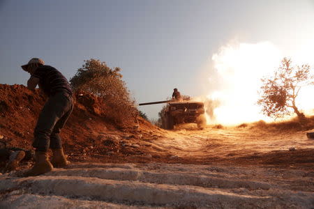 A rebel fighter of the Al-Furqan brigade covers his ears as a fellow fighter fires a vehicle's weapon during what the rebels said is an offensive to take control of the al-Mastouma army base which is controlled by forces loyal to Syria's President Bashar al-Assad near Idlib city May 17, 2015. REUTERS/Khalil Ashawi