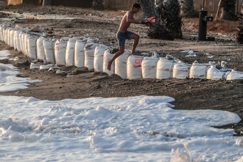 San Juan Capistrano, CA, Wednesday, August 19, 2021 - A swimmer escapes the rising tide at Capistrano Beach where large sandbags had been placed to mitigate erosion from this week's unusually high tide surf. (Robert Gauthier/Los Angeles Times)