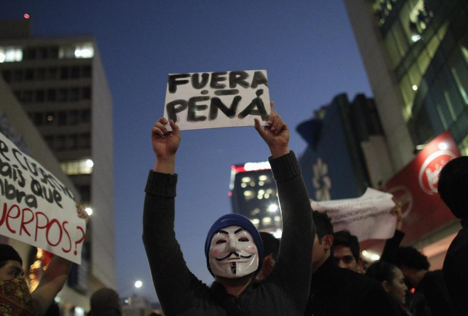 A demonstrator wears a Guy Fawkes mask while holding a sign reading "Pena (Mexico's President Enrique Pena Nieto) Out" during a protest in support of 43 missing Ayotzinapa students, in Monterrey