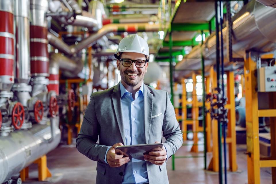 Person in business attire holding electronic table at an industrial facility.