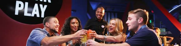 A group of people toasting beers at Dave & Buster's.