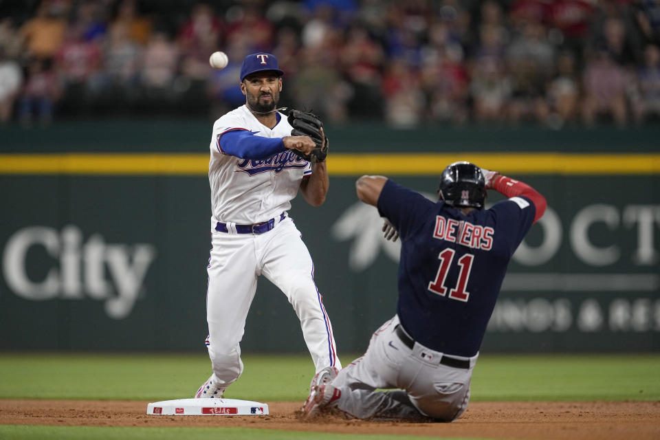 Texas Rangers second baseman Marcus Semien throws to first to complete the double play after getting the force on Boston Red Sox's Rafael Devers (11) in the first inning of a baseball game in Arlington, Texas, Monday, Sept. 18, 2023. Rob Refsnyder was out at first on the play. (AP Photo/Tony Gutierrez)