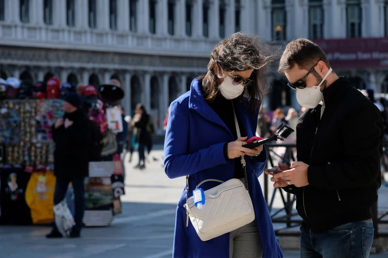 Tourists wear protective masks in Saint Mark's Square in Venice as Italy battles a coronavirus outbreak