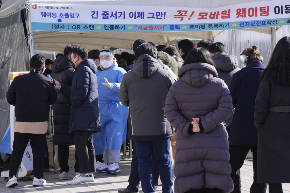 A medical worker guides people as they wait for their coronavirus test at a makeshift testing site in Seoul, South Korea, Friday, Jan. 28, 2022. (AP Photo/Ahn Young-joon)