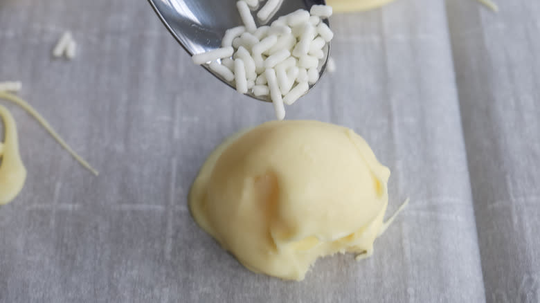 white chocolate truffle on sheet, spoon dropping sprinkles