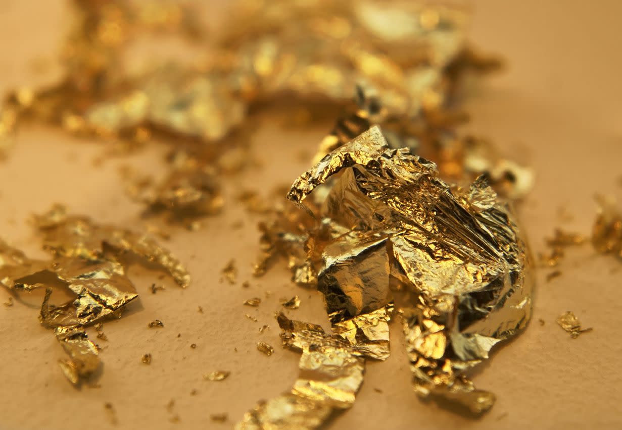 A pile of pricey gold leaves on a gold background.