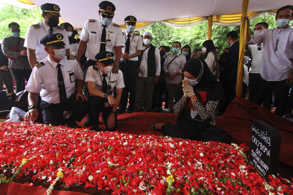 Relatives pray at the grave of Okky Bisma, a steward, one of victim Sriwijaya Air passenger jet crashed during his funeral in Jakarta, Indonesia.Thursday, Jan. 14, 2021. An aerial search for victims and wreckage of a crashed Indonesian plane expanded Thursday as divers continued combing the debris-littered seabed looking for the cockpit voice recorder from the lost Sriwijaya Air jet.(AP Photo)