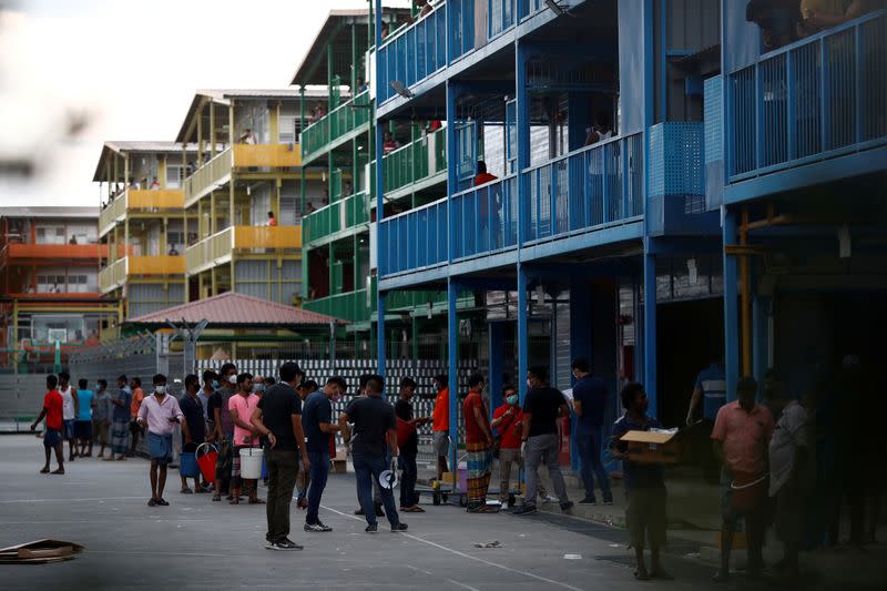 FILE PHOTO: Workers from Bangladesh, India and China queue up with buckets to collect food at Punggol S-11 workers' dormitory, which was gazetted to be an isolation facility after it became a cluster of coronavirus cases (COVID-19), in Singapore