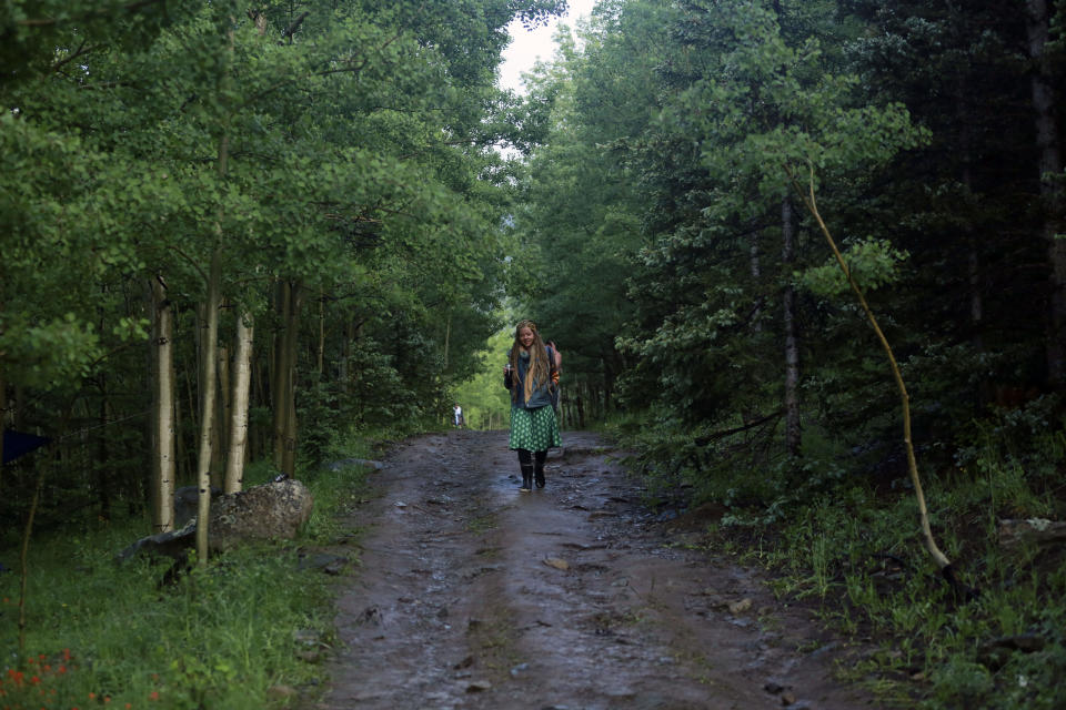 Kendra Strebig walks between encampments at the Rainbow Gathering on Friday, July 2, 2021, in the Carson National Forest, outside of Taos, N.M. More than 2,000 people have made the trek into the mountains of northern New Mexico as part of an annual counterculture gathering of the so-called Rainbow Family. While past congregations on national forest lands elsewhere have drawn as many as 20,000 people, this year’s festival appears to be more reserved. Members (AP Photo/Cedar Attanasio)