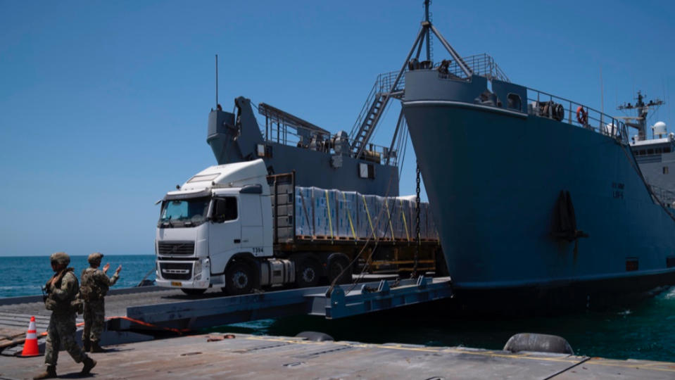 運送救援物資的貨車25日經由美軍搭建的浮動碼頭，將物資送上岸。美聯社