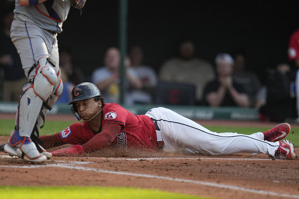 Cleveland Guardians' Josh Naylor, right, slides home behind New York Mets catcher Tomás Nido, left, to score during the third inning of a baseball game Tuesday, May 21, 2024, in Cleveland. (AP Photo/Sue Ogrocki)